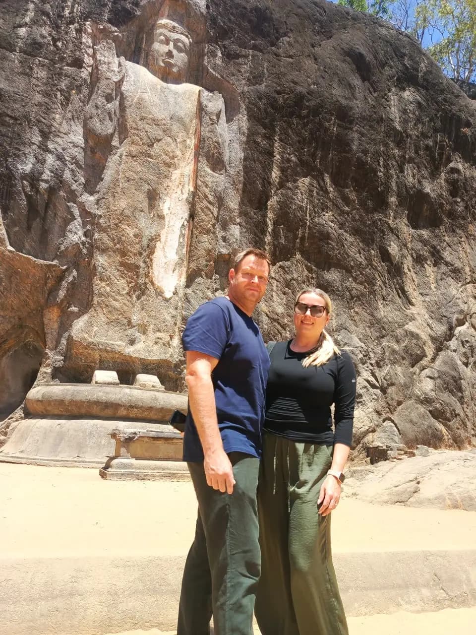 Couple marveling at colossal 10th-century Buduruwagala rock carvings in Wellawaya